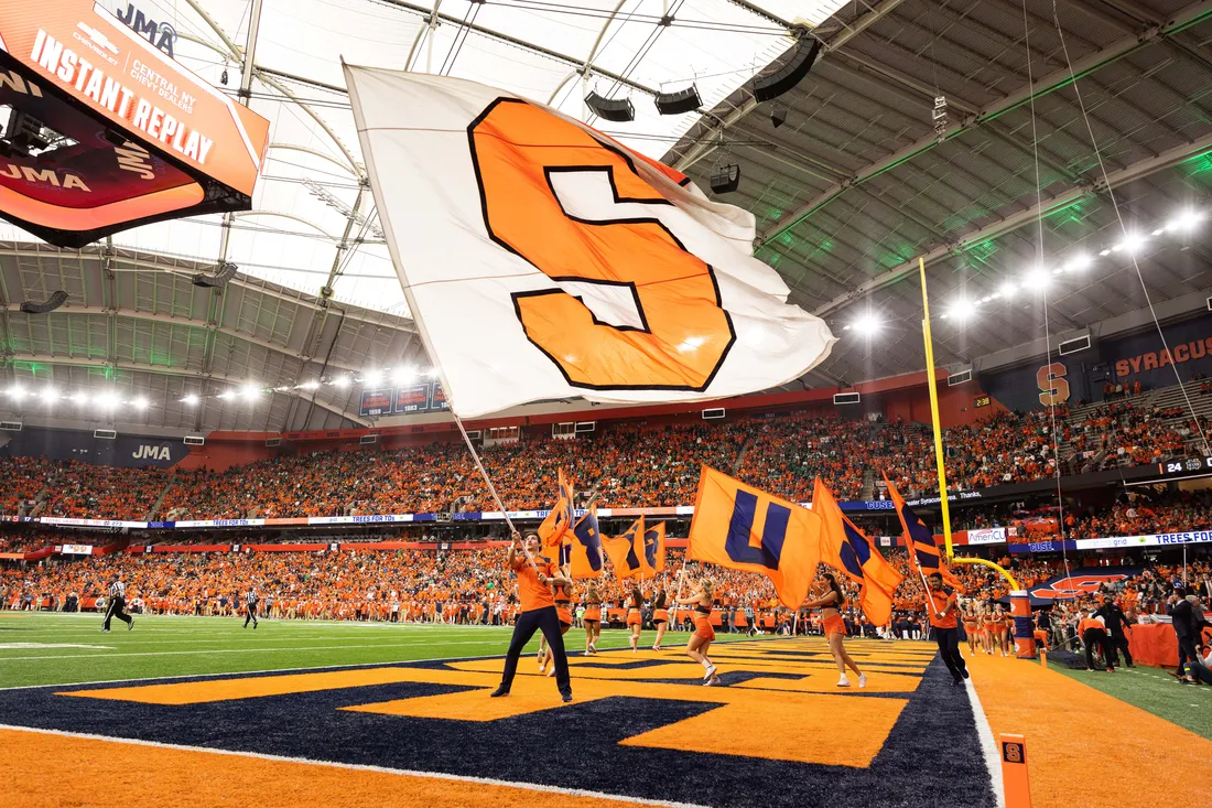 Syracuse University flag being waved on stadium JMA Wireless stadium field.