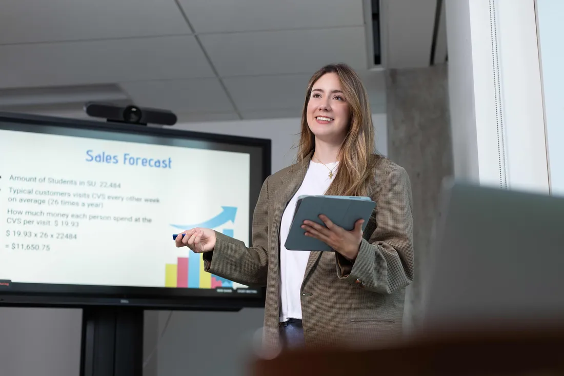 A student standing in a classroom giving a presentation.