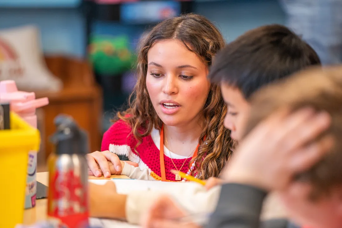 Student of the School of Education teaching a young student in a classroom.