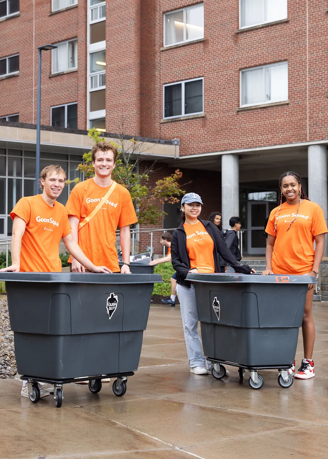 Student pushing a cart and smiling at the camera.