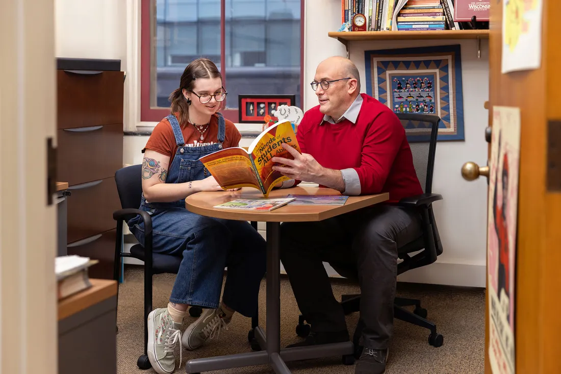 George Theoharis reading a book with a student.