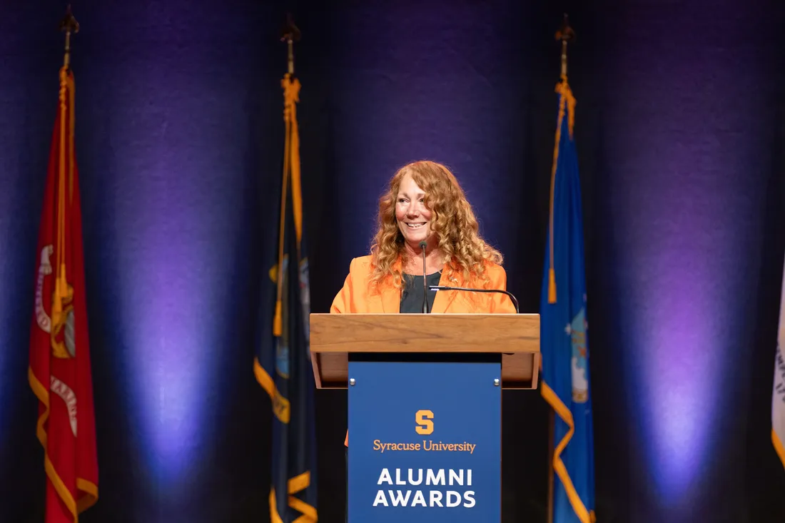 Peggy Combs at a podium speaking.