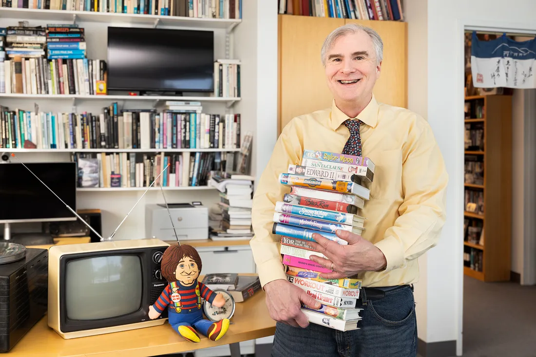 Person holding a stack of movies.