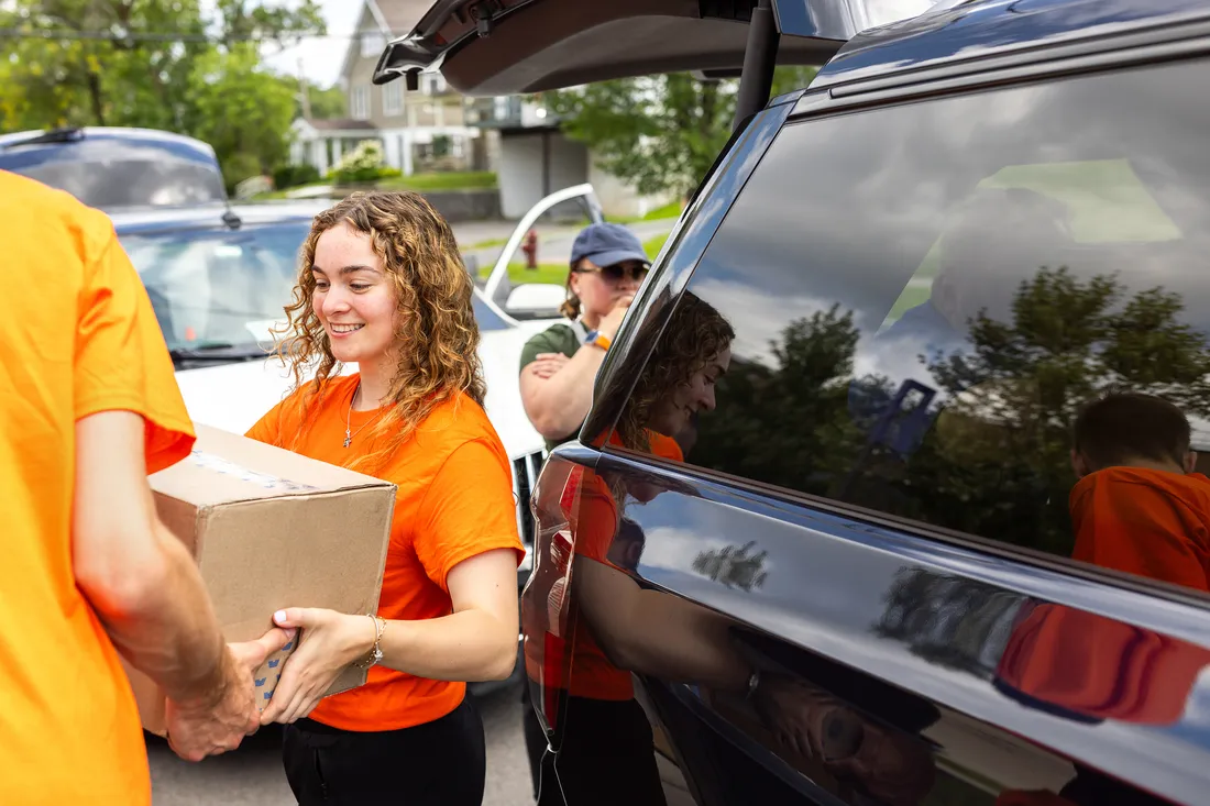 Student worker passing a box to another person.