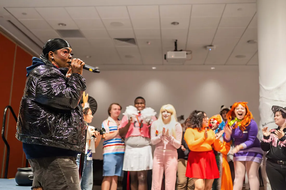 Someone talking into a microphone while others cheer.