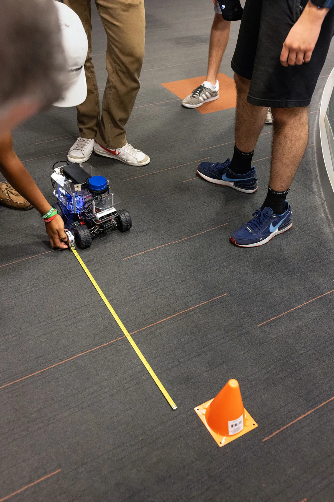 Students measure distance between AI robotic car and cone.