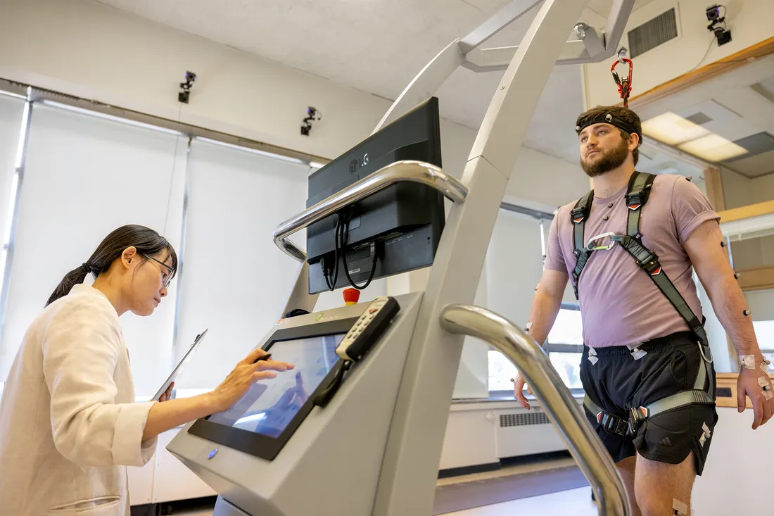 Person walking on a treadmill while a researcher collects data.