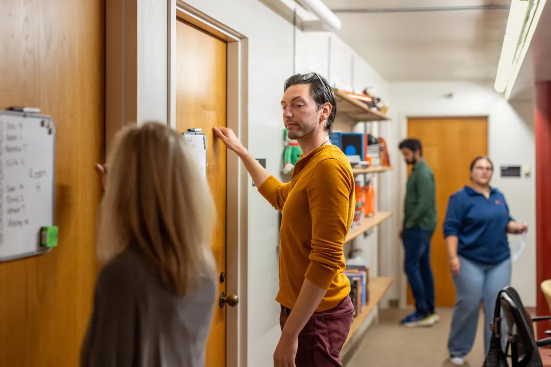 Students writing on a white board on a door.