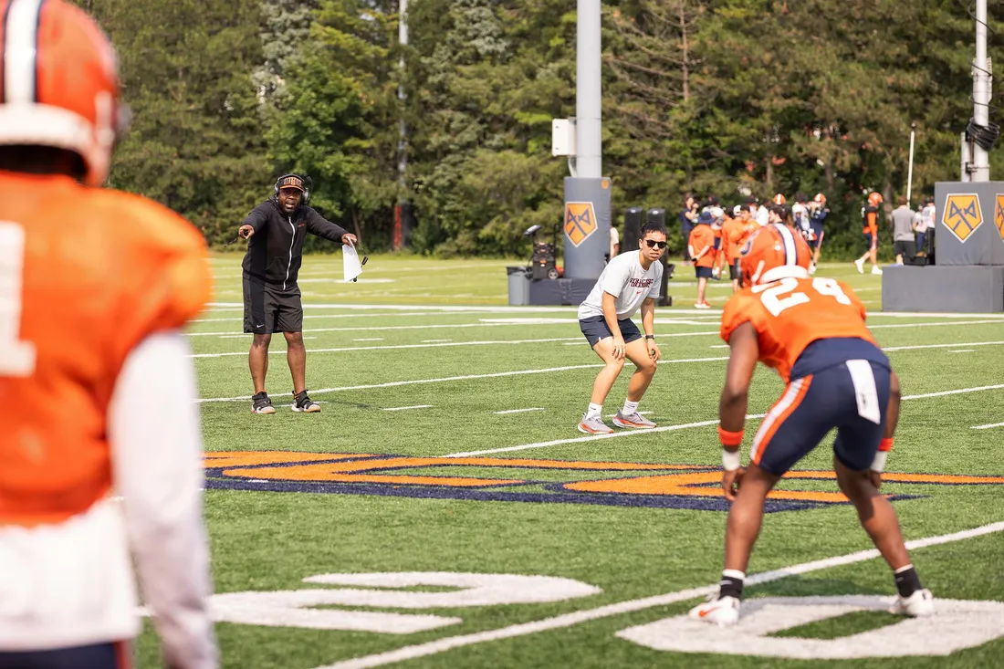 Fran Brown on the field with players.