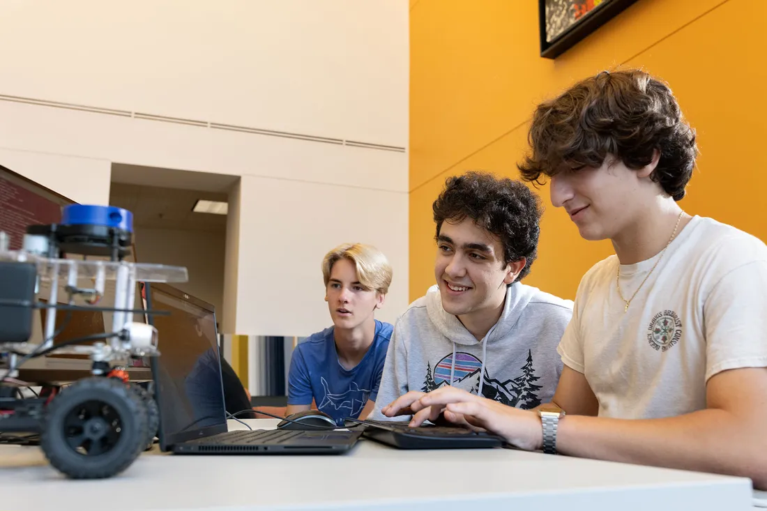 Students work around laptop programming AI car.