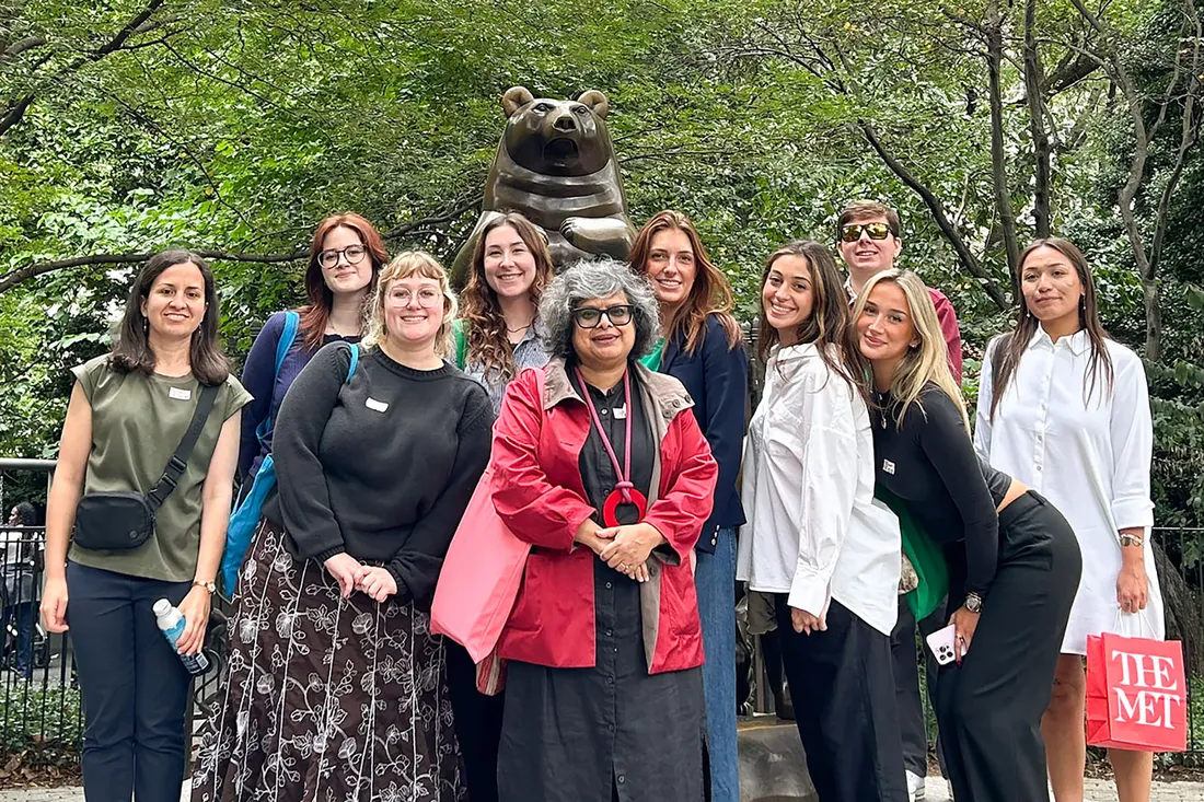 Group of students and faculty smiling at a camera outside.