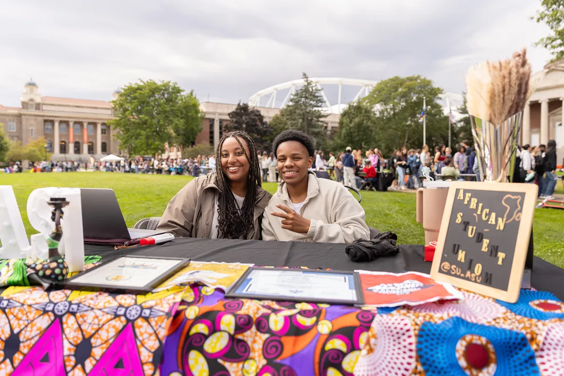 Students sitting at table at involvement fair promoting African Student Union Organization.