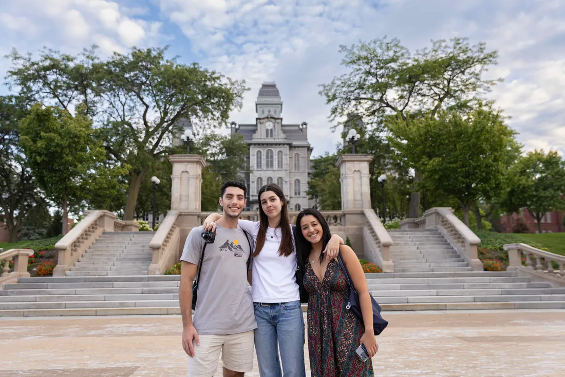 International students standing outside of the Hall of Languages smiling.