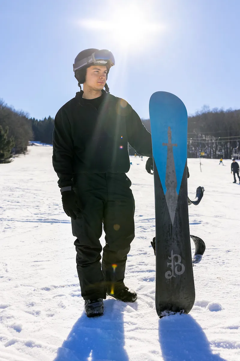 A person holding a snowboard on a hill.