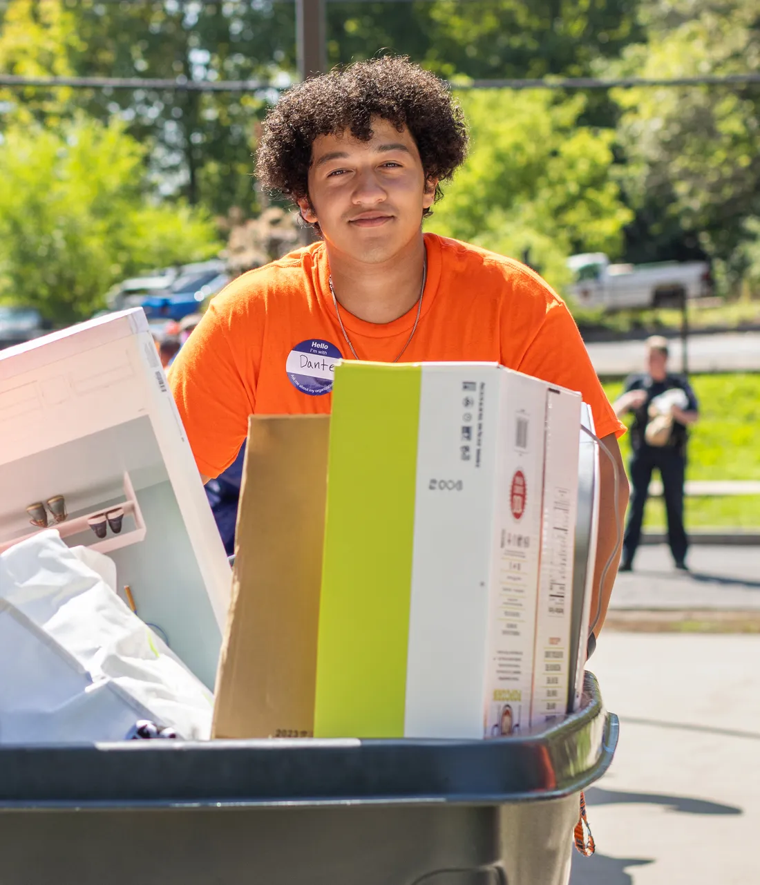 Student pushing a cart and smiling at the camera.