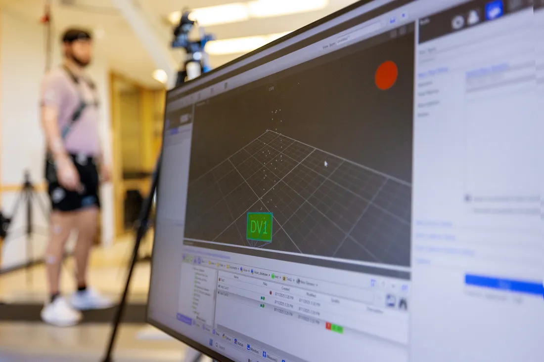 A computer screen with data and a test subject in a lab.