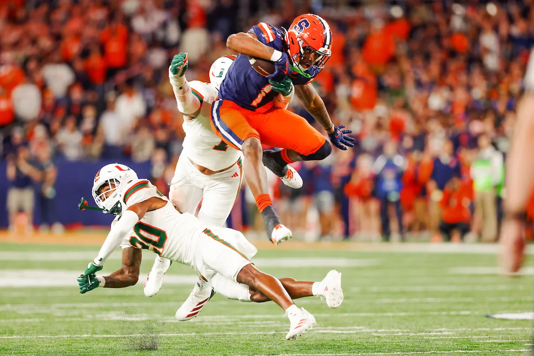 LeQuint Allen jumping over other football players.