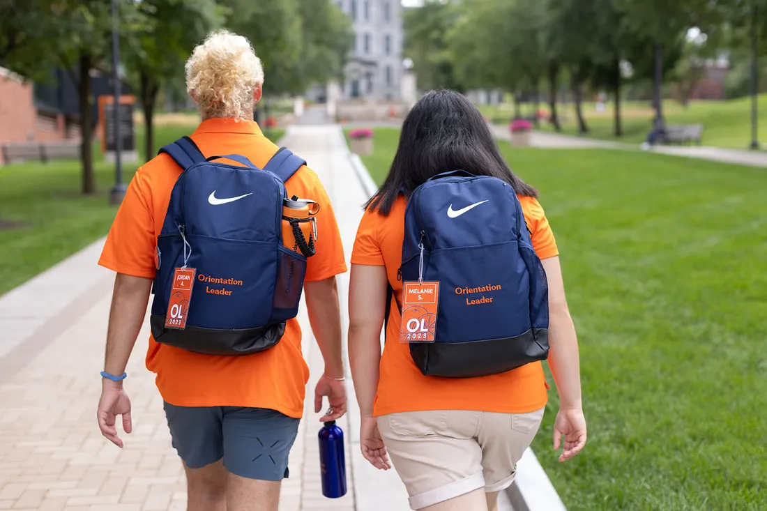 Orientation leaders walk away from camera wearing custom backpacks with "Orientation Leader" embroidered on them.