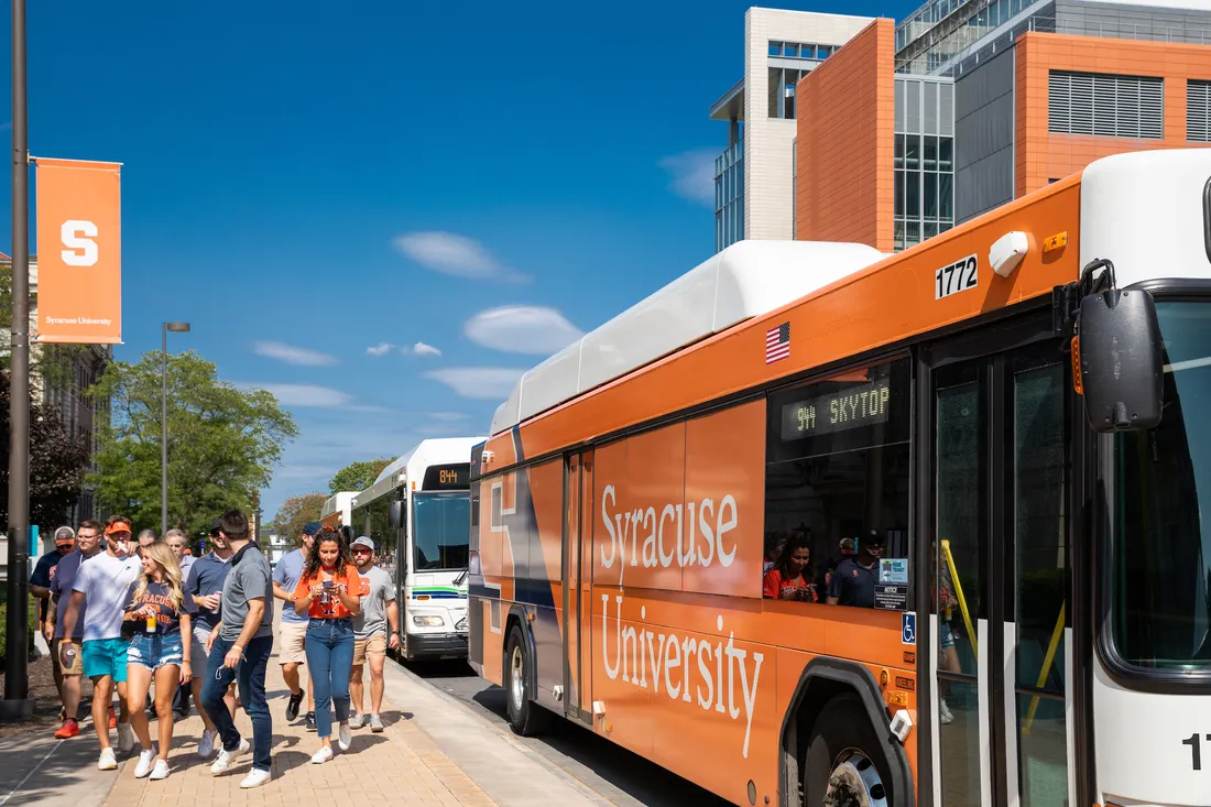 People getting off a bus on campus.