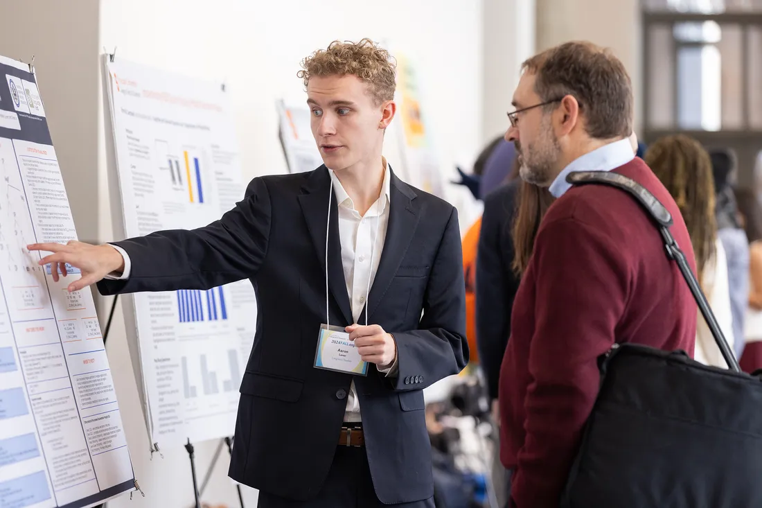 Aaron Learner pointing at his research at the SOURCE symposium.