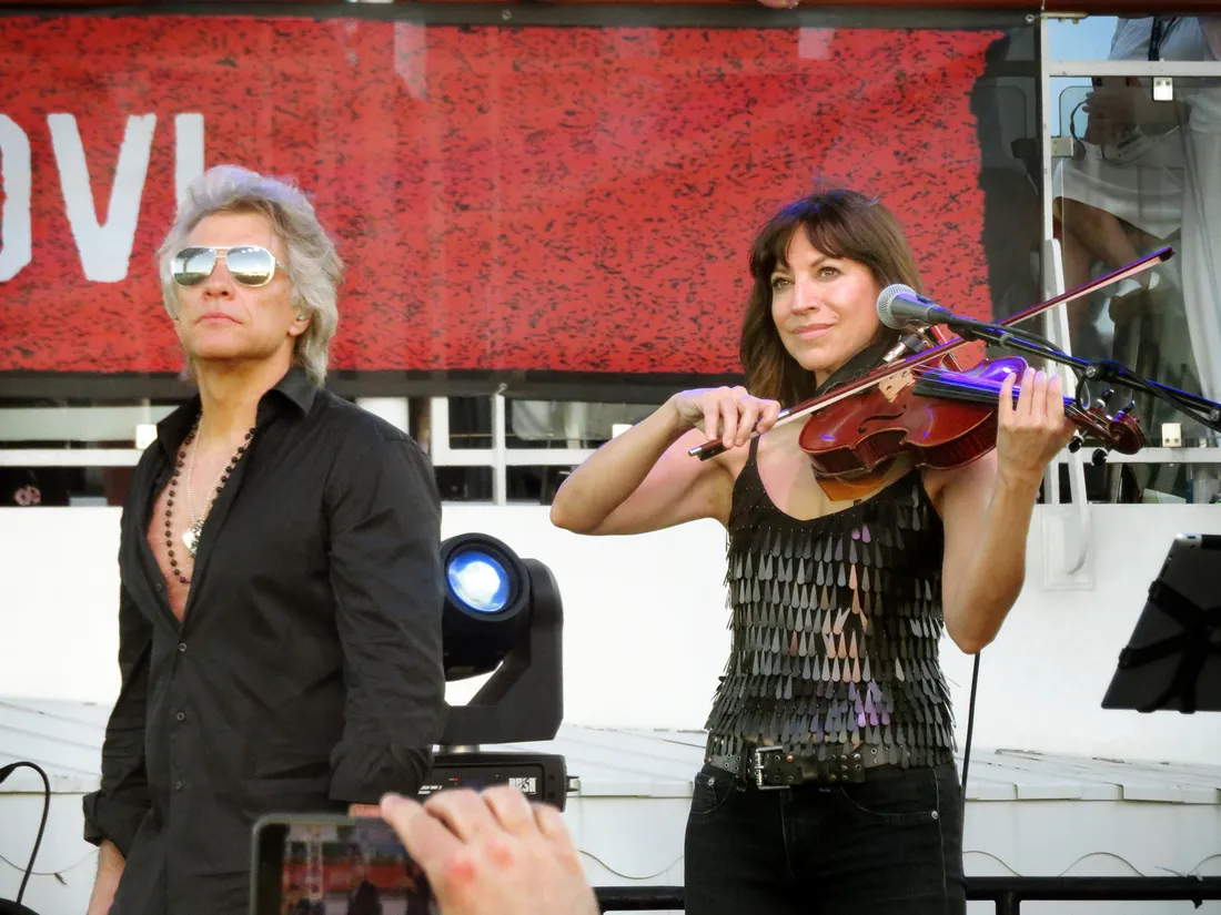 Lorenza Ponce playing violin next to Bon Jovi.