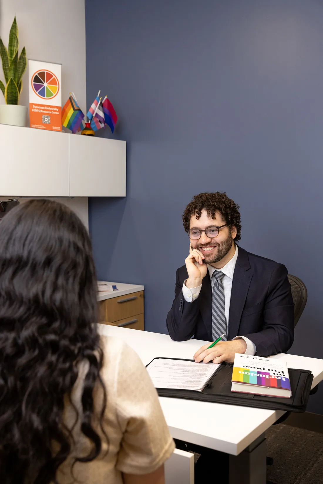 Joshua Sequí-Rodriguez talking with a person at his desk.