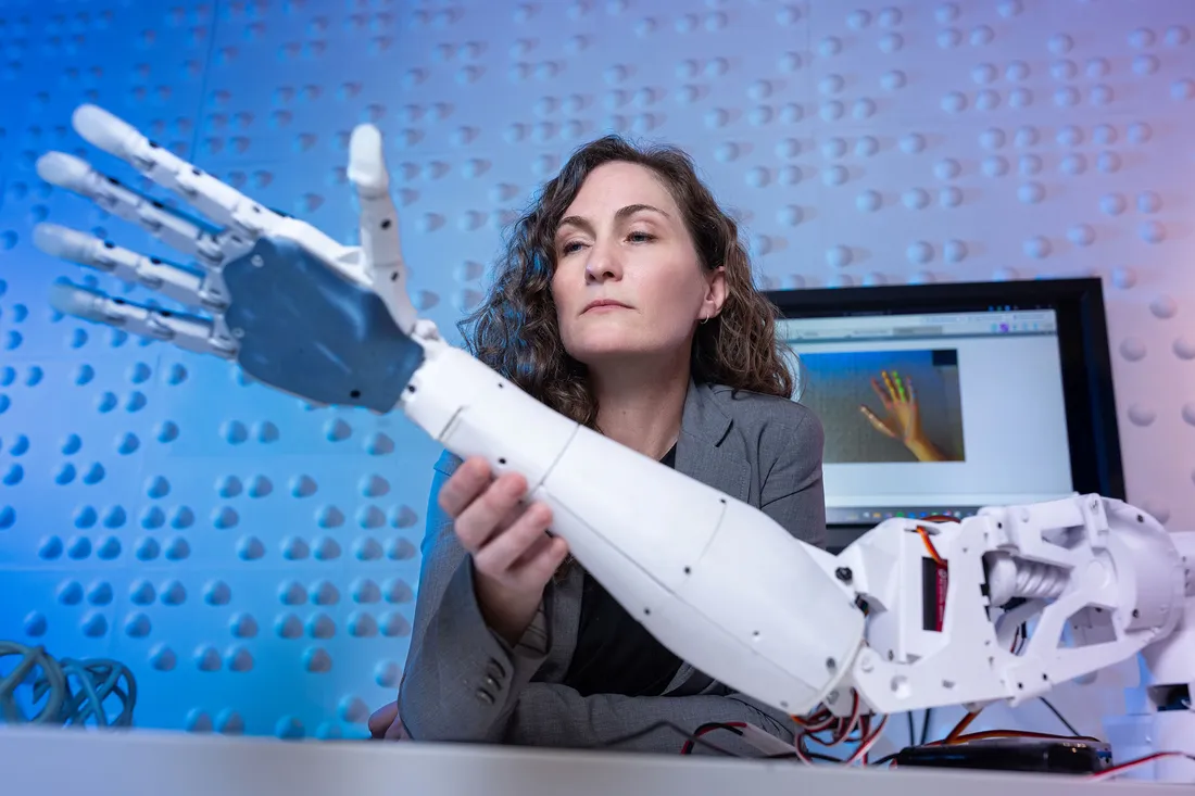 Jaime Banks holding a robotic arm.