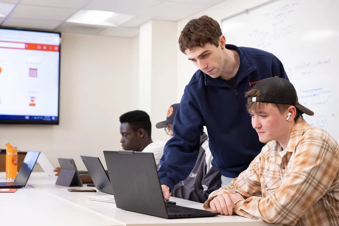 Student Oliver Raycroft looking at a computer with a friend.