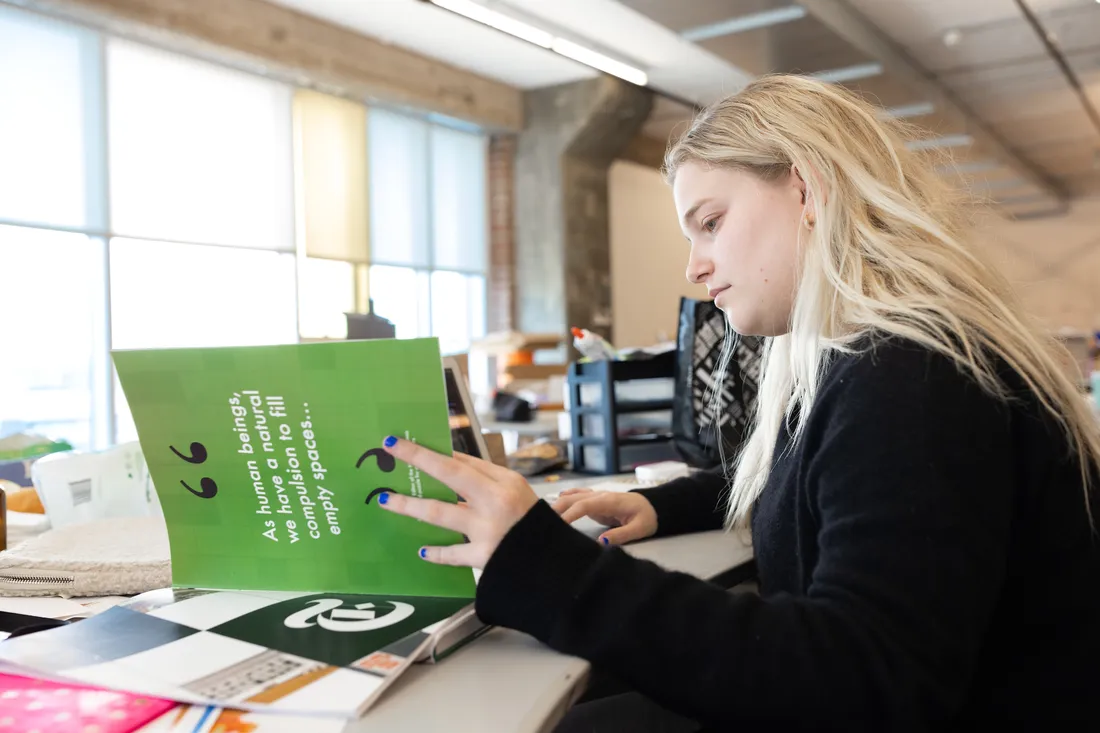 A person reading an art book in a classroom.